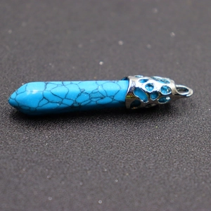 Macro shot of turquoise hexagonal pillar pendant with silver hollowed metal wrap detailing