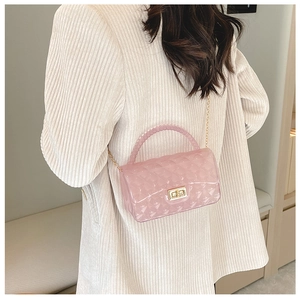 Pink transparent jelly bag with quilted pattern worn over the shoulder by a model
