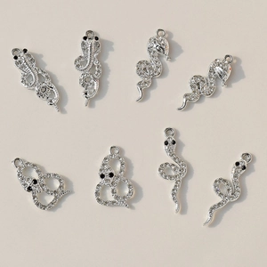 Silver snake charms with white cubic zirconia and black stone eyes in flat lay