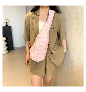 Sac bandoulière matelassé rose en nylon porté par un mannequin avec un costume