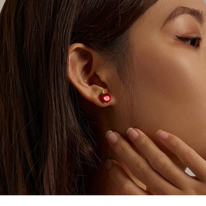 Close-up of a model wearing red apple shaped silver stud earrings for Christmas holiday