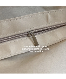 Detailed macro view of the smooth metal zipper head on a beige woven canvas handbag