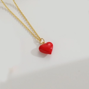 Close-up of red enamel heart pendant on a gold chain necklace with smooth finish