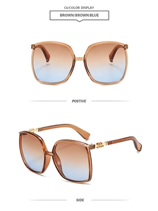 Detailed view of oversized brown gradient sunglasses with stylish metal temples and logo