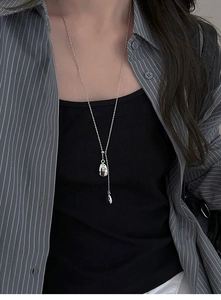 Detail of silver long Y-shaped necklace with irregular geometric pendant on model