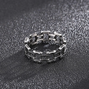 Vue macro d'une bague à maillons argentée au style punk industriel sur un fond sombre