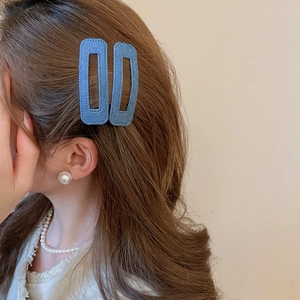 Detail of blue denim textured rectangular hair clips and matching pearl jewelry on model