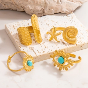 Close-up of 18k gold rings with turquoise and evil eye designs on white stone