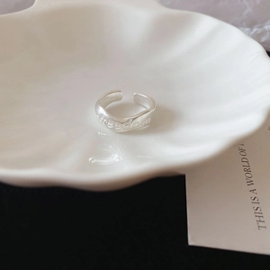 Macro shot of silver S925 ring with freedom engraving on a white shell plate