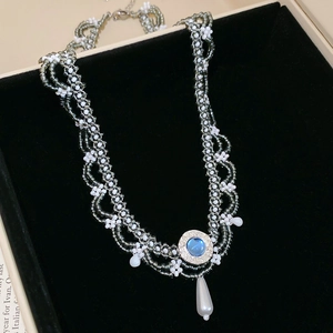 Macro shot of ethnic pearl necklace with blue gemstone and lace beadwork detail