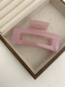 Close-up of a translucent pink square hair claw clip with a sleek gold spring mechanism