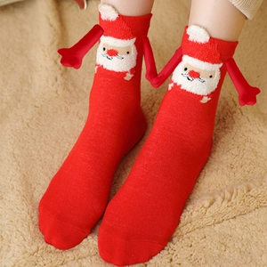 Festive red Christmas socks with 3D Santa heads and magnetic holding hands on soft rug