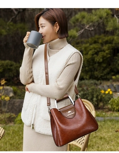 Brown PU leather tote bag with unique metal handle and shoulder strap shown outdoors