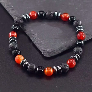 Volcanic rock beads bracelet with red Bagua charms on a dark stone surface