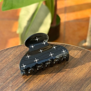 Elegant black acetate shark hair claw clip with sparkling rhinestones on wood surface
