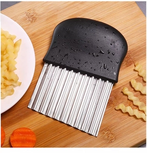 Macro detail of wavy stainless steel blade slicing potato on a wooden board
