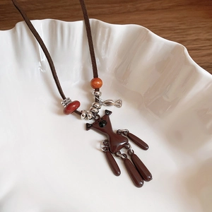 Detail of a brown puppet pendant with articulated limbs on a velvet cord necklace