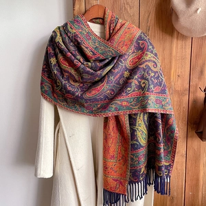 Close-up of ethnic paisley cashmere-like scarf with tassels on a white wool coat