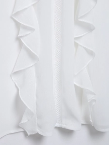 Detail of white chiffon blouse featuring ruffle trim and vertical lace stitching detail
