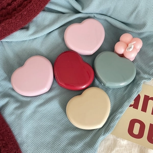Flat lay of colorful heart-shaped contact lens cases on soft textured fabric backgrounds
