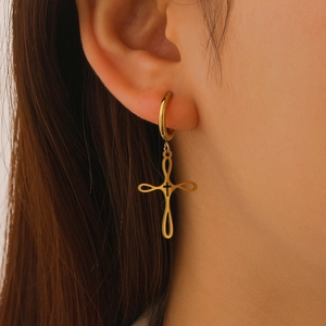 Close-up of a gold-plated stainless steel hollow cross earring worn by a model