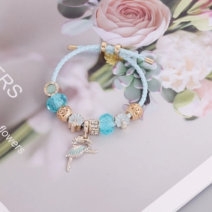 Detail of light blue braided bracelet with ballet dancer charm and blue crystal beads