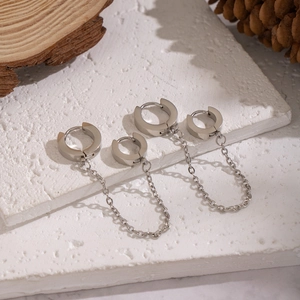 Boucles d'oreilles punk en argent poli avec de longues chaînes sur un plateau en pierre