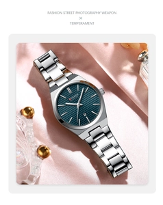 Detailed view of silver quartz watch with navy blue dial on elegant pink silk background