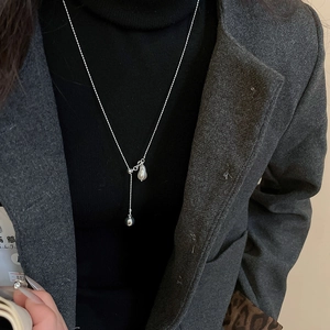 Detail of a minimalist silver Y-shaped necklace with a baroque pearl pendant and metal bead