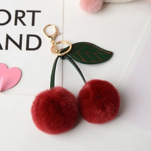 Close-up of faux rabbit fur cherry keychain with deep red plush balls and gold metal clasp