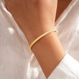 Detail of 18k gold plated bracelet with vertical textured patterns on model's wrist