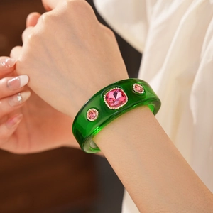 Macro detail of vintage emerald resin bangle with purple gemstones on female wrist