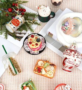 Detailed view of festive glass Christmas ornaments featuring cake and drink shapes on pine