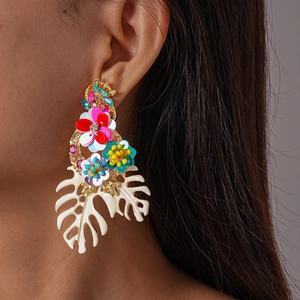 Detailed view of oversized bohemian earrings with colorful floral sequins and white leaf