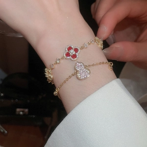 Macro shot of 18k gold plated bracelets with red clover and sparkling gourd charms
