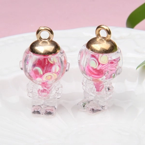 Close-up of astronaut glass ball pendants with pink sequins and gold metal loops