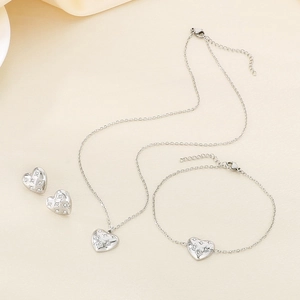 Elegant silver heart jewelry set with necklace bracelet and earrings on soft fabric