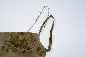Detail of tie-dye dress with brown flocked floral pattern and metal chain strap
