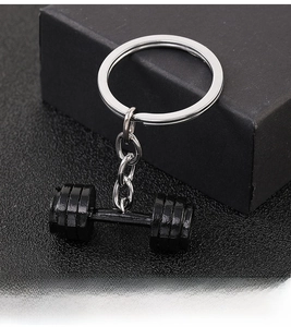 Close-up of black dumbbell keychain with silver metal ring on textured dark background