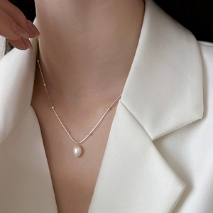 Minimalist stainless steel necklace with white pearl pendant worn on female neck