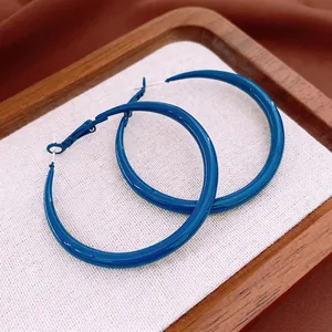 Klein blue hoop earrings with silver needles in a wooden tray for vintage fashion style