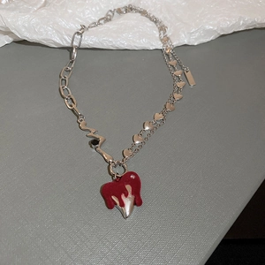Detail of silver chain necklace with red melting heart pendant and asymmetric punk style links