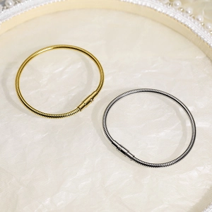 Detailed view of gold and silver snake chain bracelets on elegant pearl background