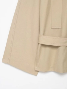 Detailed macro view of khaki trench coat hem showing premium twill fabric and stitching
