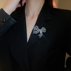 Detailed view of luxury bow brooch with purple and green zircons on a black suit jacket