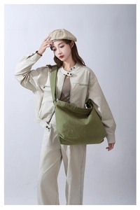 Dettaglio di una grande borsa a tracolla in tela di cotone verde indossata da una modella