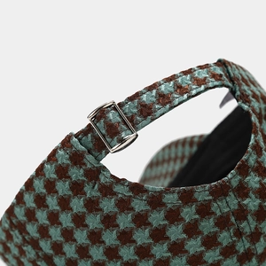 Detailed view of the adjustable silver metal buckle on a houndstooth pattern baseball cap
