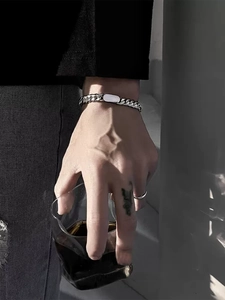 Close-up of silver steel cuban link bracelet with rectangular ID plate on wrist