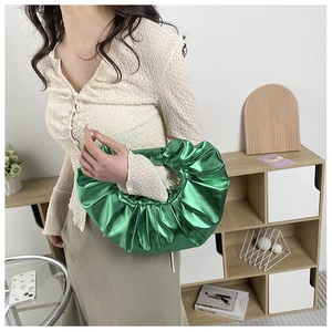 Makroaufnahme der metallisch grünen Plissee-Handtasche mit Glanz-Finish und Textur