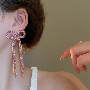 Detail of pink crystal bowknot earrings with long tassels on a model for a refined look